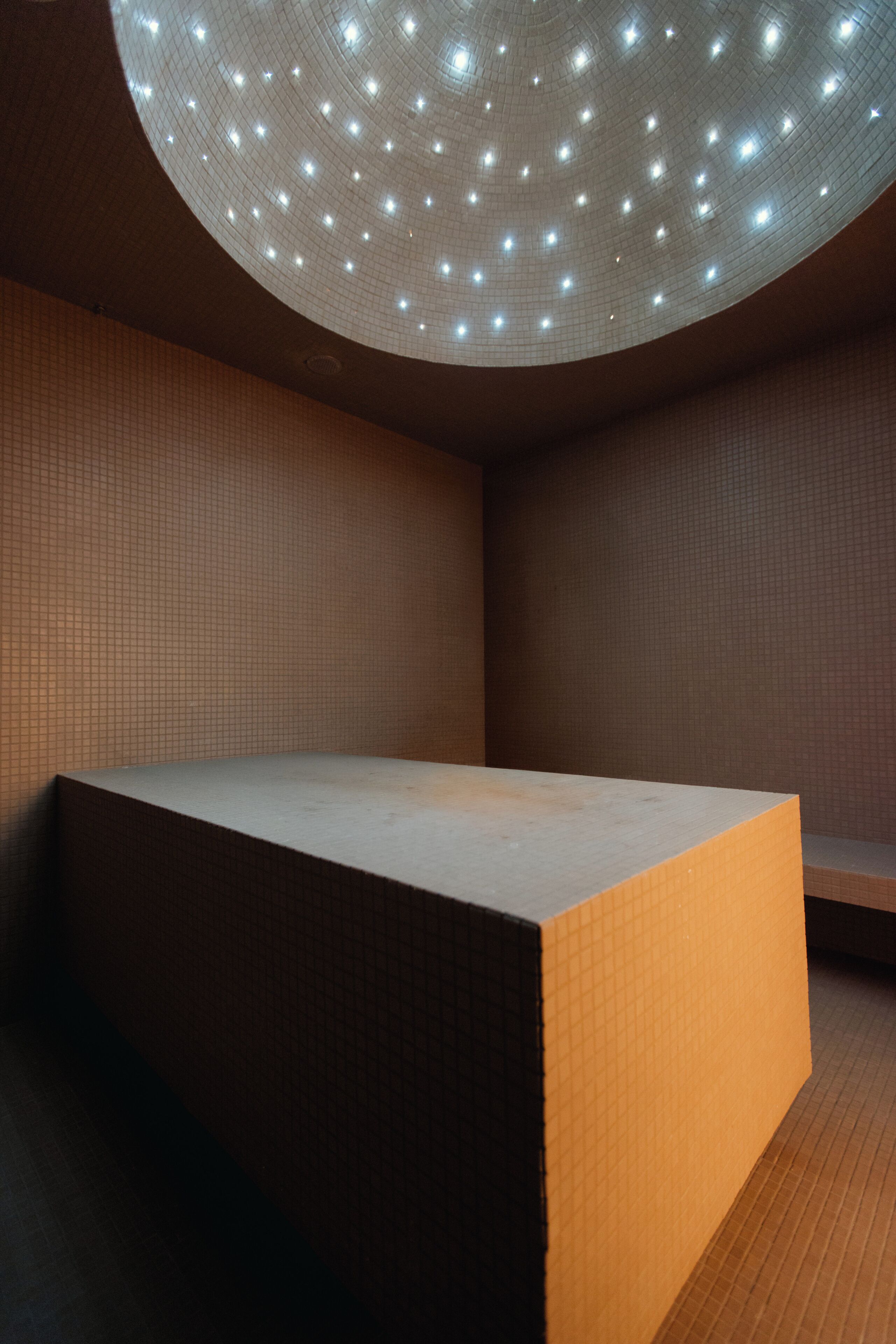 A room with a recessed ceiling, a flat surface, and a tiled wall.