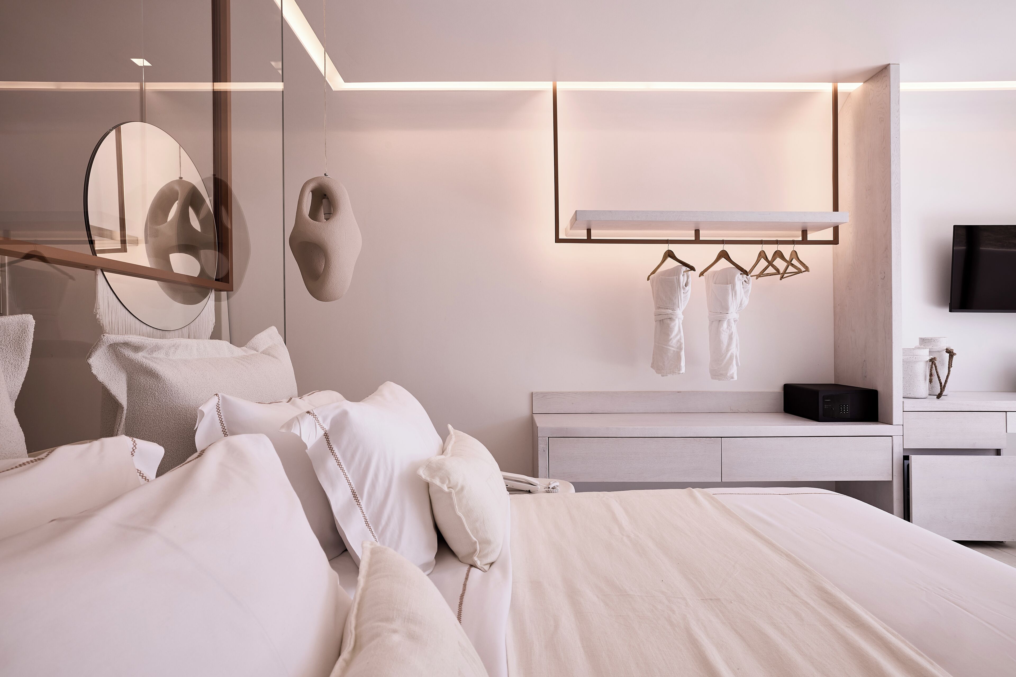 A modern bedroom with a large bed, bedside tables, a mirror, and a TV mounted on the wall.