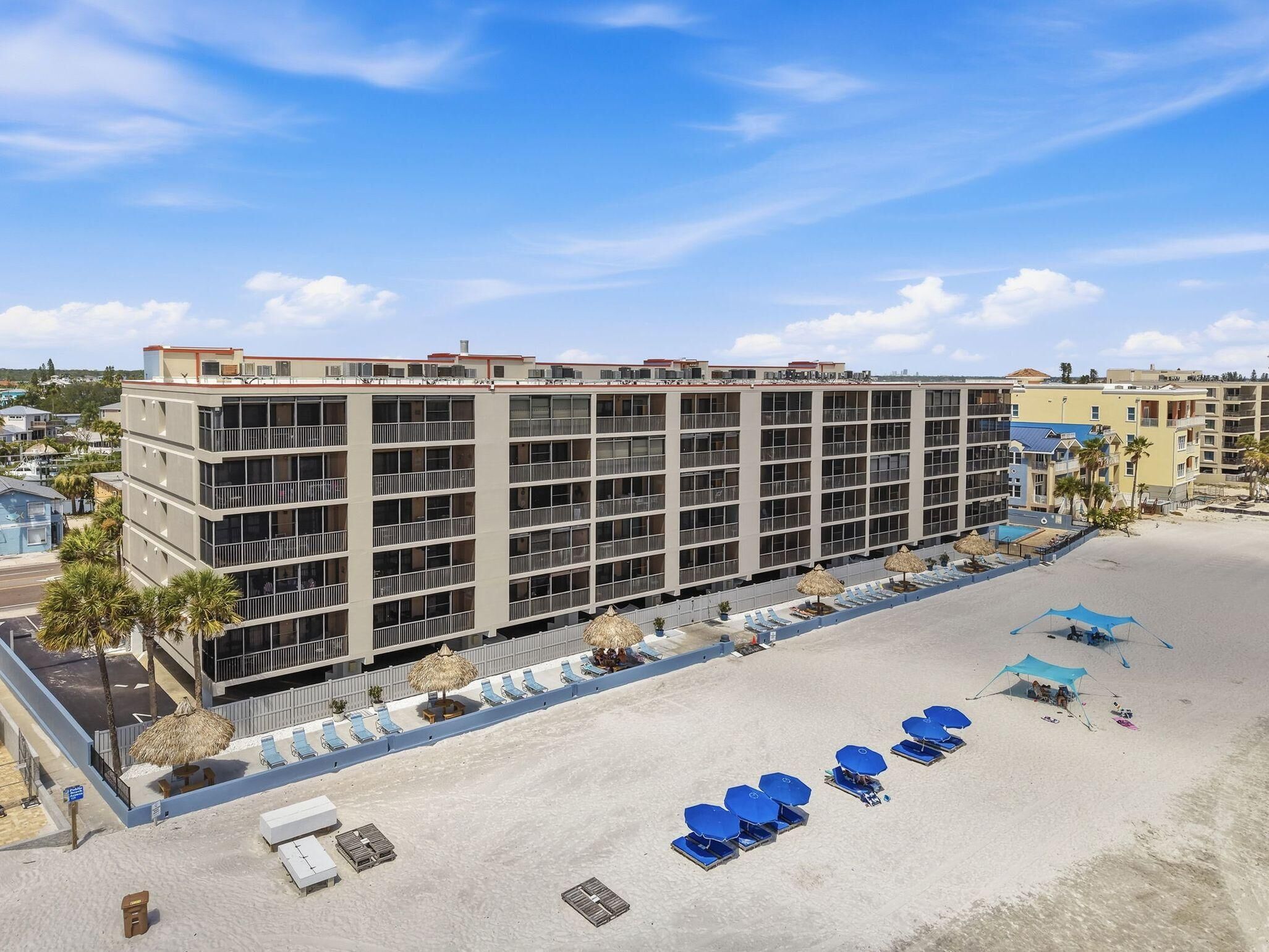 Un hôtel à plusieurs étages doté de balcons, d’un espace piscine et de sièges installés au bord de la plage.