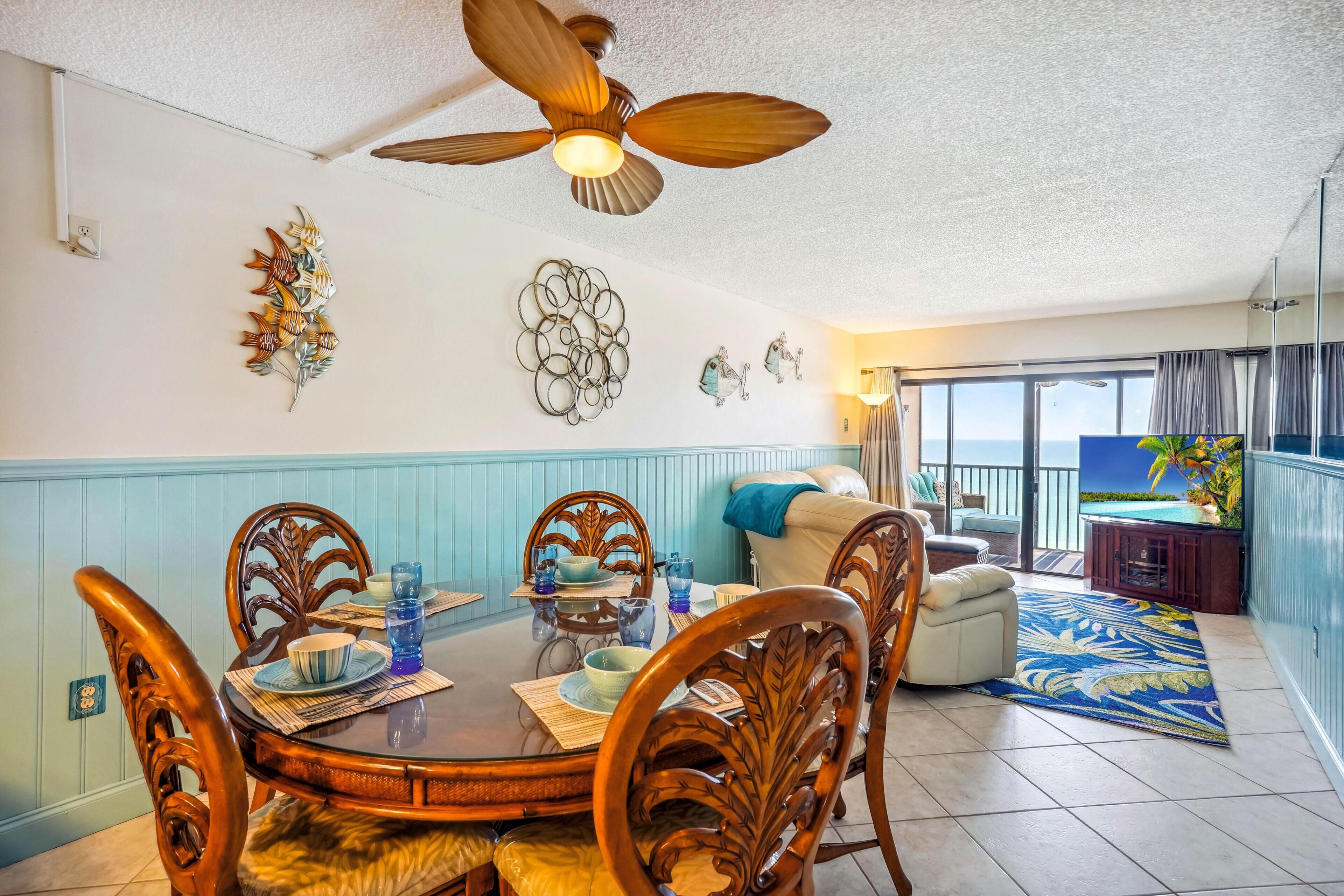 A dining area with a round table, wooden chairs, and a ceiling fan.