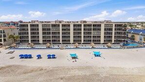 A hotel with multiple balconies, a pool, and beach umbrellas.
