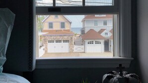 Ein Schlafzimmer mit einem Fenster, das auf eine Nachbarschaft blickt.