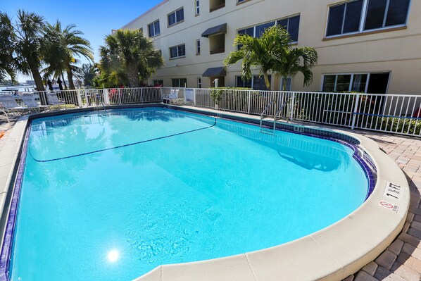 A rectangular pool with a white metal fence and a tiled edge. - Westwinds 213 (Treasure Island)