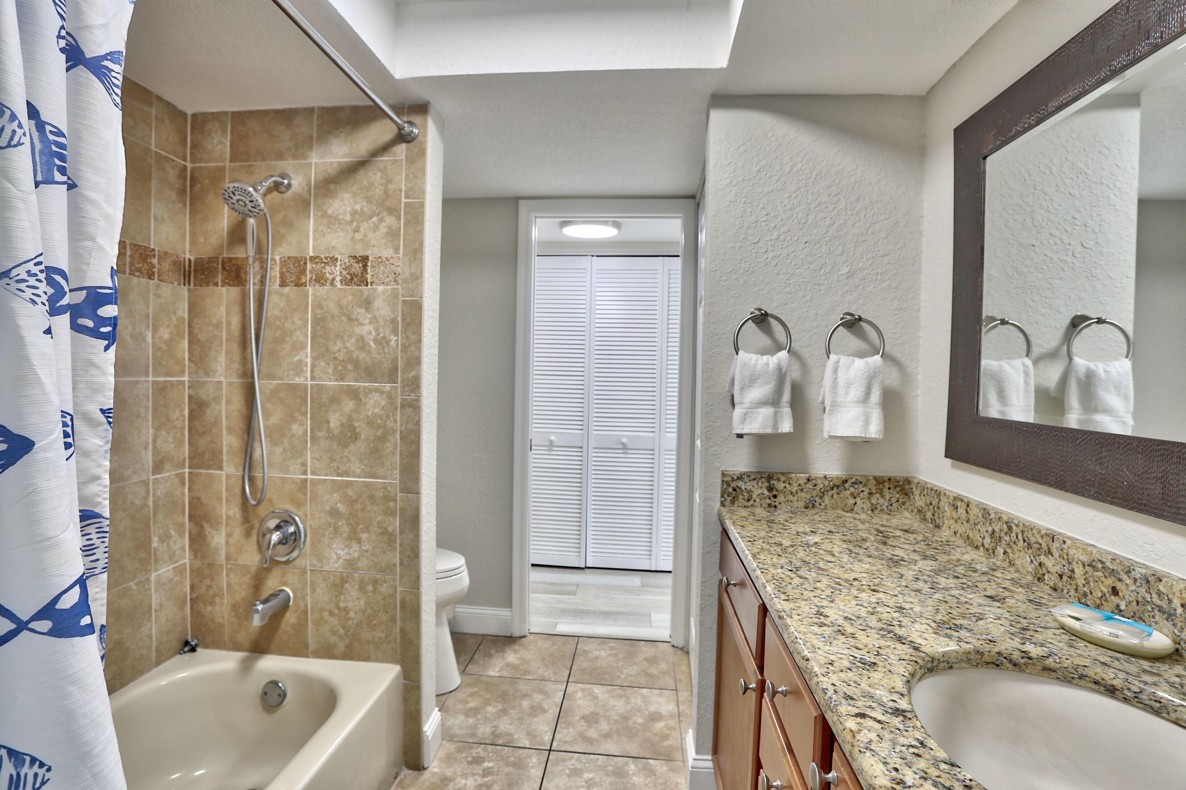 A bathroom with a bathtub, shower, toilet, and a vanity with a sink and mirror.