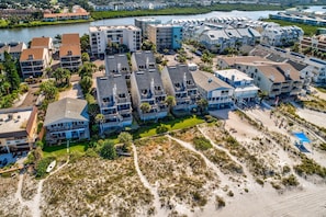 An aerial view of a coastal hotel with multiple buildings, a beach, and a body of water.
