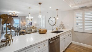 A modern kitchen with a marble countertop, stainless steel appliances, and pendant lighting. - Pelican Pointe 5B (Indian Shores)