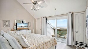 A bedroom with a bed, a television, a ceiling fan, and a view of the outside. - Pelican Pointe 5B (Indian Shores)