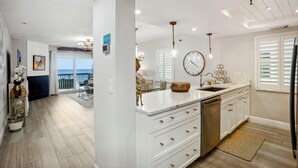 A modern kitchen with white cabinetry, a large island, and a view to the outside. - Pelican Pointe 5B (Indian Shores)