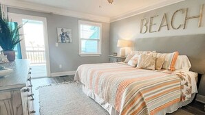 A bedroom with a bed, a ceiling fan, a window, and a wall with the word "BEACH" on it. - Oceanview condo in heart of PSJ Beach (Port St. Joe)