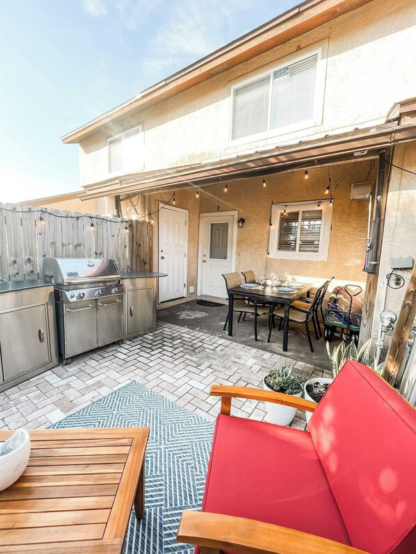 Ein Garten mit Grill, einem Esstisch und Stühlen sowie einer Holzterrasse.