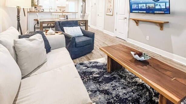 A living room with a sofa, armchair, coffee table, and a TV mounted on the wall. - Oceanview condo in heart of PSJ Beach (Port St. Joe)