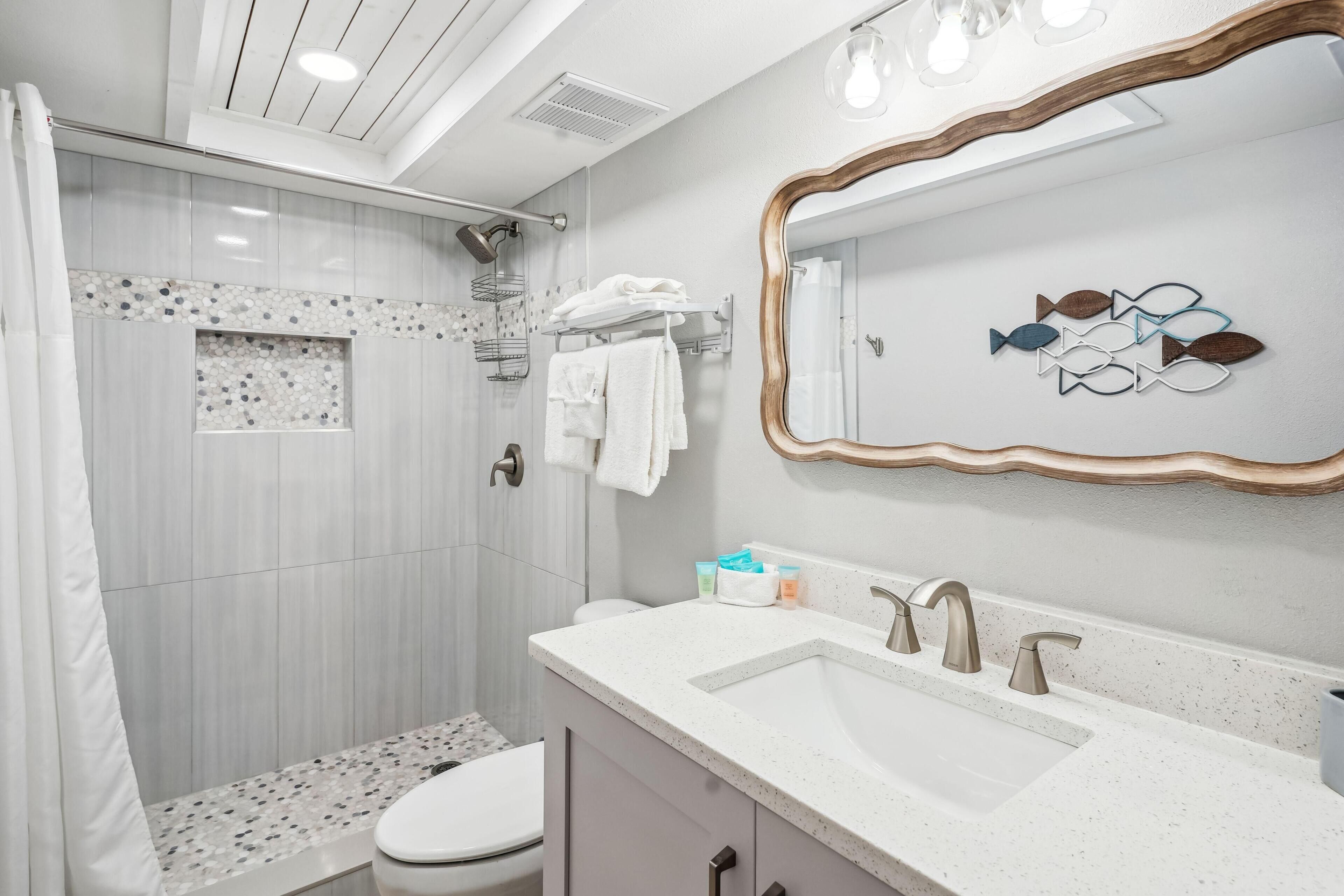 A modern bathroom with a shower, toilet, and vanity with a large mirror and two sinks.