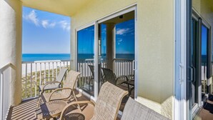 A balcony with a view of the ocean, furnished with wicker chairs and a table. - Sunset Vistas 501w (Treasure Island)