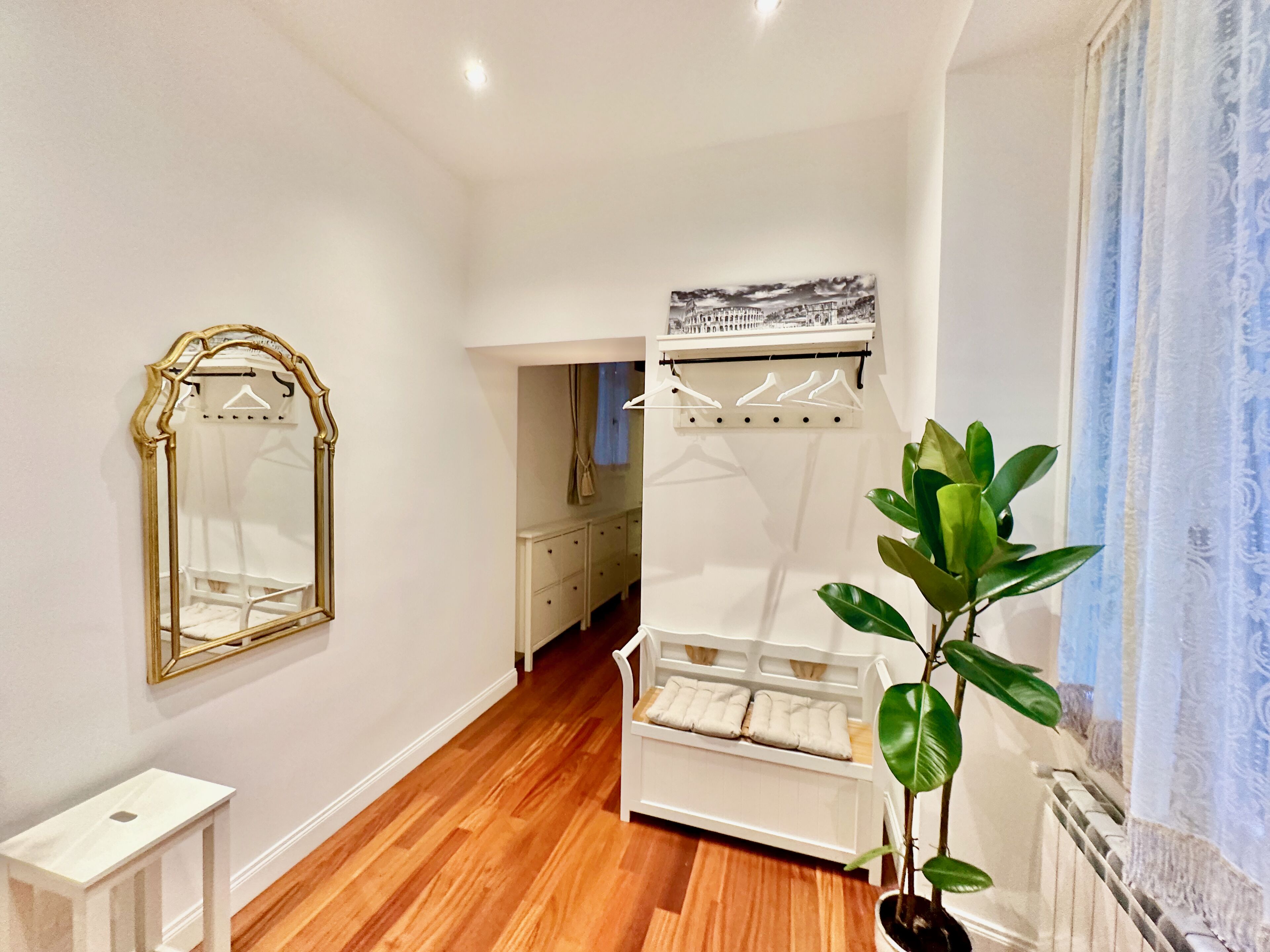 A bedroom with a bed, a dresser, a mirror, and a plant.