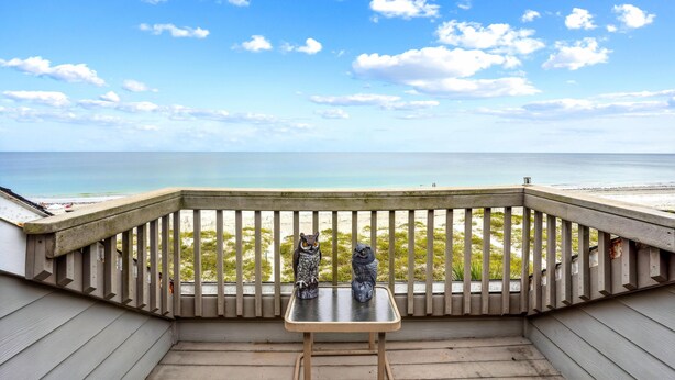 A wooden deck with a railing overlooking a beach and ocean. - Pelican Pointe 3B (Indian Shores)