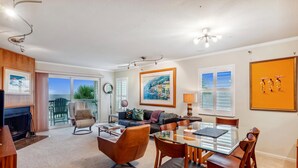 A spacious living area with a fireplace, a dining table with chairs, a sofa, and a large window with a view. - Pelican Pointe 3B (Indian Shores)