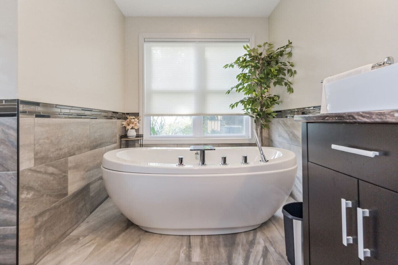 Een moderne badkamer met een vrijstaand bad, een raam en een potplant.