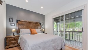 A bedroom with a large bed, wooden headboard, two bedside tables with lamps, and a balcony with a railing. - (A)  Elora Grand River Suite (Elora)