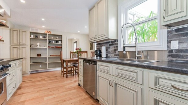 A kitchen with light-colored cabinets, a stone backsplash, and a window with a view of greenery. - (A)  Elora Grand River Suite (Elora)