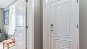 A hallway with white doors, a wooden bench, and a grey couch. - (C) Elora Riverview Flat (Elora)