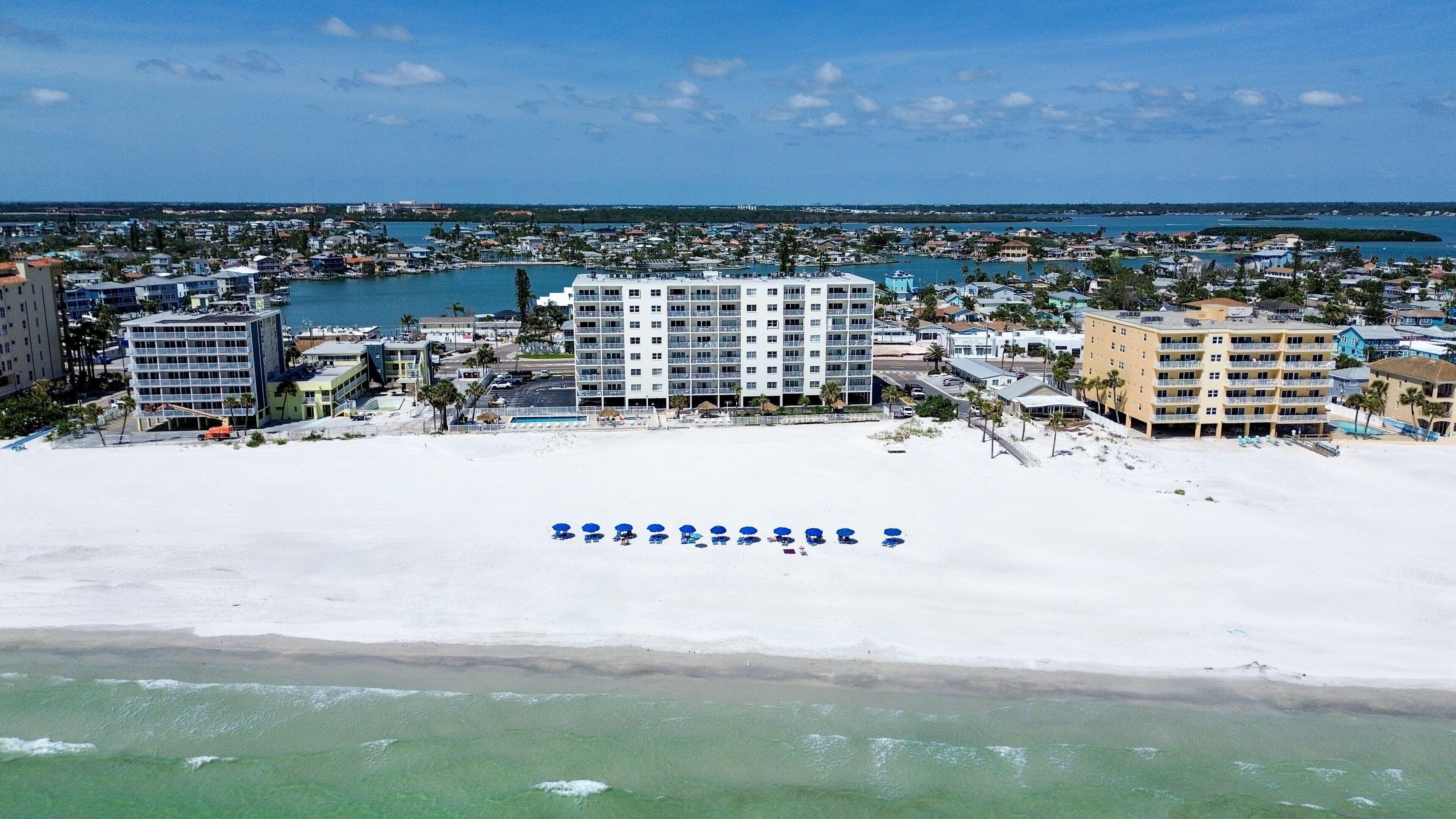 A coastal resort with multiple hotel buildings, a sandy beach, and a marina.