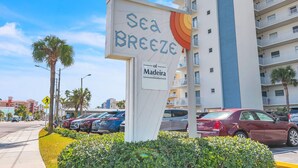 Segnaletica dell'hotel 'Sea Breeze' con una palma e auto parcheggiate sullo sfondo.