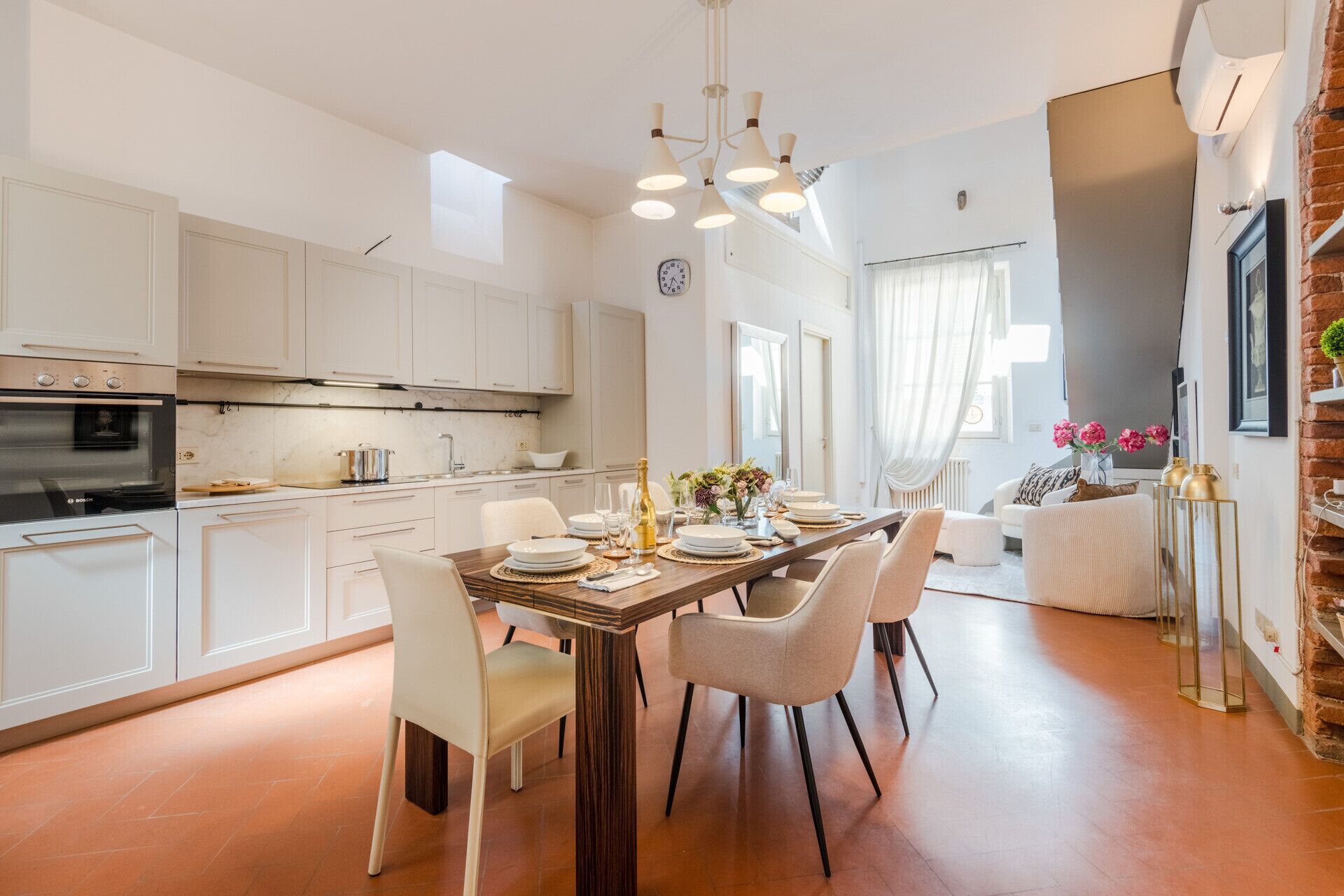 Eine moderne Küche mit weißen Schränken, einem Backofen von Bosch und einem Essbereich mit einem Holztisch und vier Stühlen.