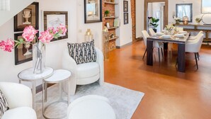 A spacious living area with a staircase, white furniture, and a dining table set for six. - Modern Panoramic Penthouse with Elevator inside the Walls of Lucca (Lucca)