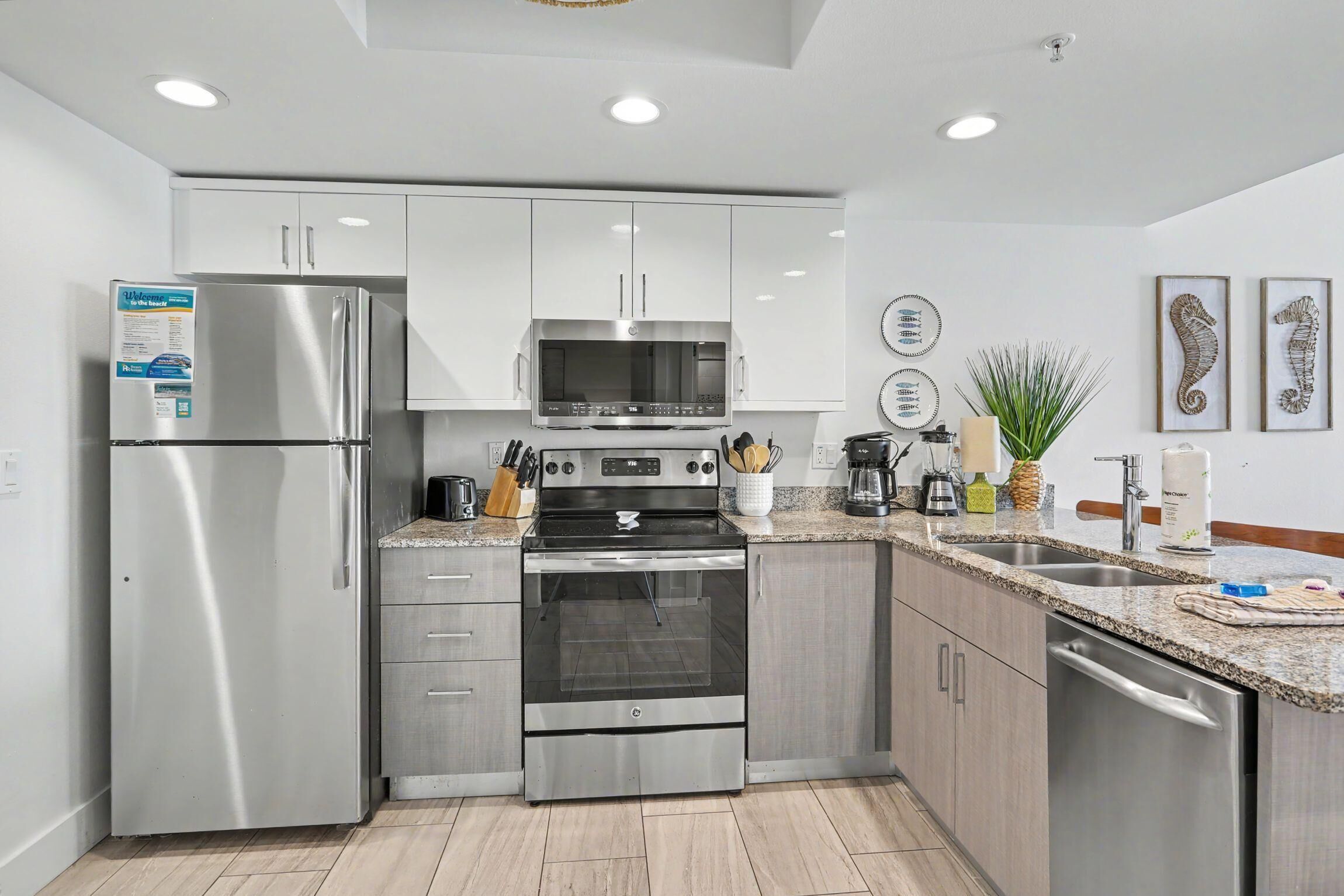 A modern kitchen with stainless steel appliances, granite countertops, and white cabinetry.