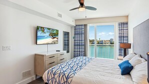 Un dormitorio con cama, televisor, ventilador de techo y vista al mar.