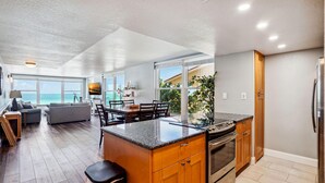 A modern kitchen with a large island, wooden cabinets, and stainless steel appliances. - Madeira Vista 201 (Madeira Beach)