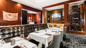 A restaurant with leather booths, white tablecloths, and a wine rack.