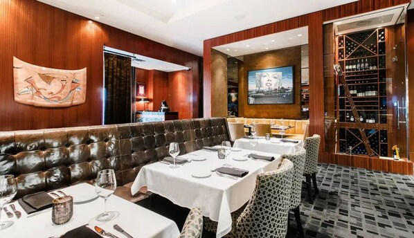A restaurant with leather booths, white tablecloths, and a wine rack.