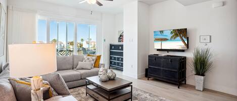 A modern living room with a grey sofa, a coffee table, a TV, and a ceiling fan.