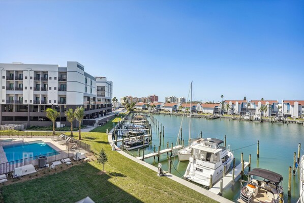 A marina with boats docked, a swimming pool, and a building with balconies.