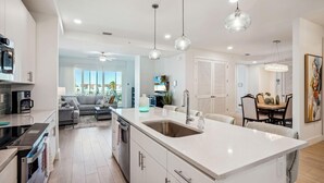 Una cocina moderna con una isla grande, armarios blancos e iluminación colgante.