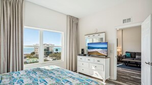 A hotel room with a bed, a TV, a dresser, and a view of the ocean. - Madeira Bay Resort I 1502 (Madeira Beach)