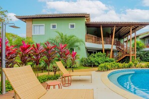 Ein Poolbereich mit Liegestühlen, einem kleinen Schwimmbecken und einem Gebäude mit Balkon.