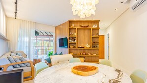 A modern living room with a round marble table, a wooden bookshelf, and a sofa with cushions. - IT22 Lindo Apto 3 Quartos a Beira Mar (Camaçari)