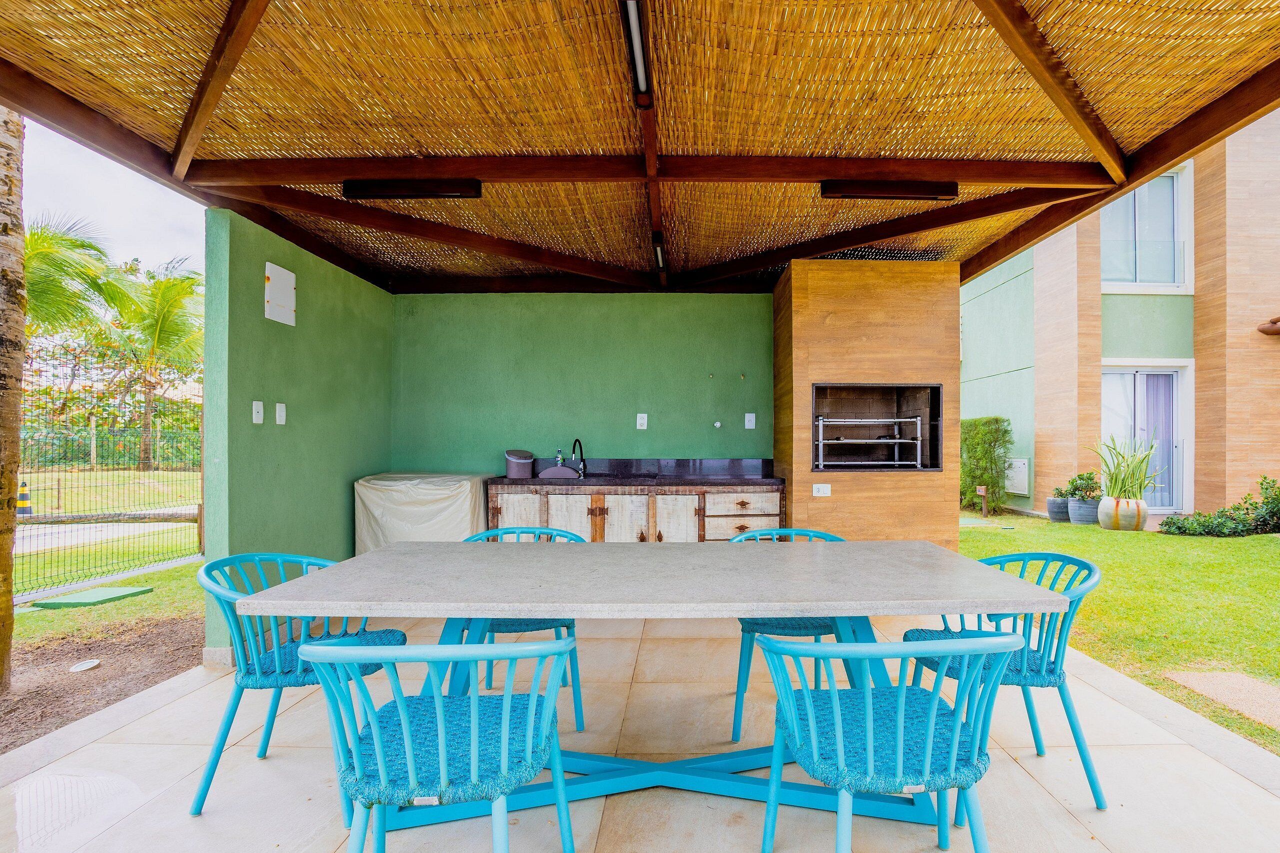 Un patio al aire libre con una mesa, sillas, una parrilla y una pared verde.