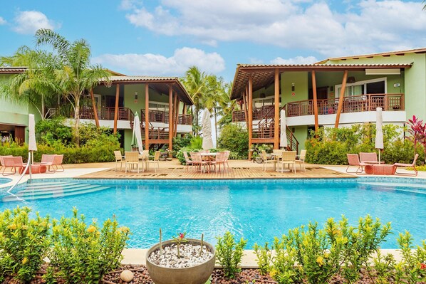 Una piscina al aire libre, sombrillas, sillones reclinables de piscina