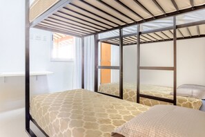 Ein Zimmer mit zwei Betten, einem Fenster und einer Tür.