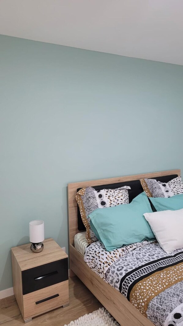 Un dormitorio con una cama, una mesita de noche y una lámpara.