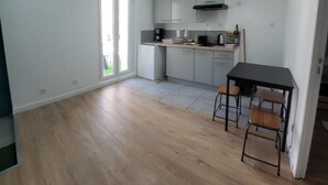 A compact kitchen with a dining area, wooden flooring, and a view through the glass door. - Maison Pour Vacances (Marseille)