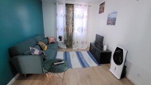 A living room with a sofa, a coffee table, a TV, and a washing machine. - Maison Pour Vacances (Marseille)