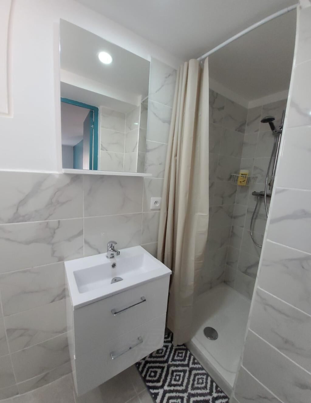 A bathroom with a white sink, a mirror, and a shower area with a glass door.
