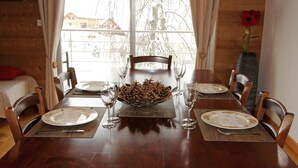 A dining table set with plates, cutlery, and a centerpiece of pinecones.