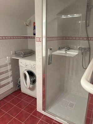 A compact bathroom with a washing machine, a glass-enclosed shower, and a sink. - Le Noirmont/ Chalet des Noisettes Appartement de 85m2 Classé 3 Avec Garage (Les Rousses)