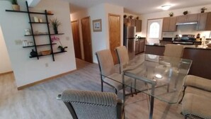 A modern kitchen with stainless steel appliances, a dining area with a glass table and chairs, and a hallway with a plant shelf. - Spacious 3-bedroom house in the Poconos. (Blakeslee)