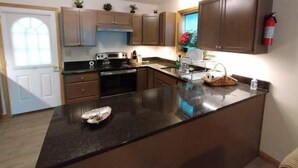 A modern kitchen with dark countertops, wooden cabinets, a stove, and a window with a view. - Spacious 3-bedroom house in the Poconos. (Blakeslee)